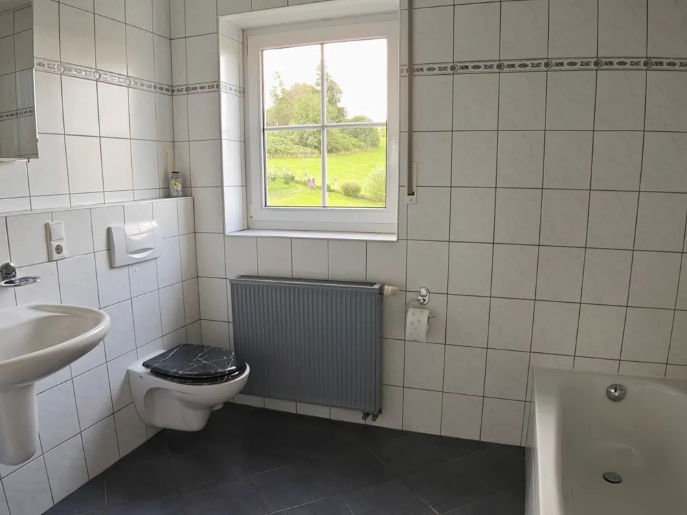 Helles Badezimmer mit Tageslichtfenster, Badewanne und Waschbecken in der Ferienwohnung in Sundern