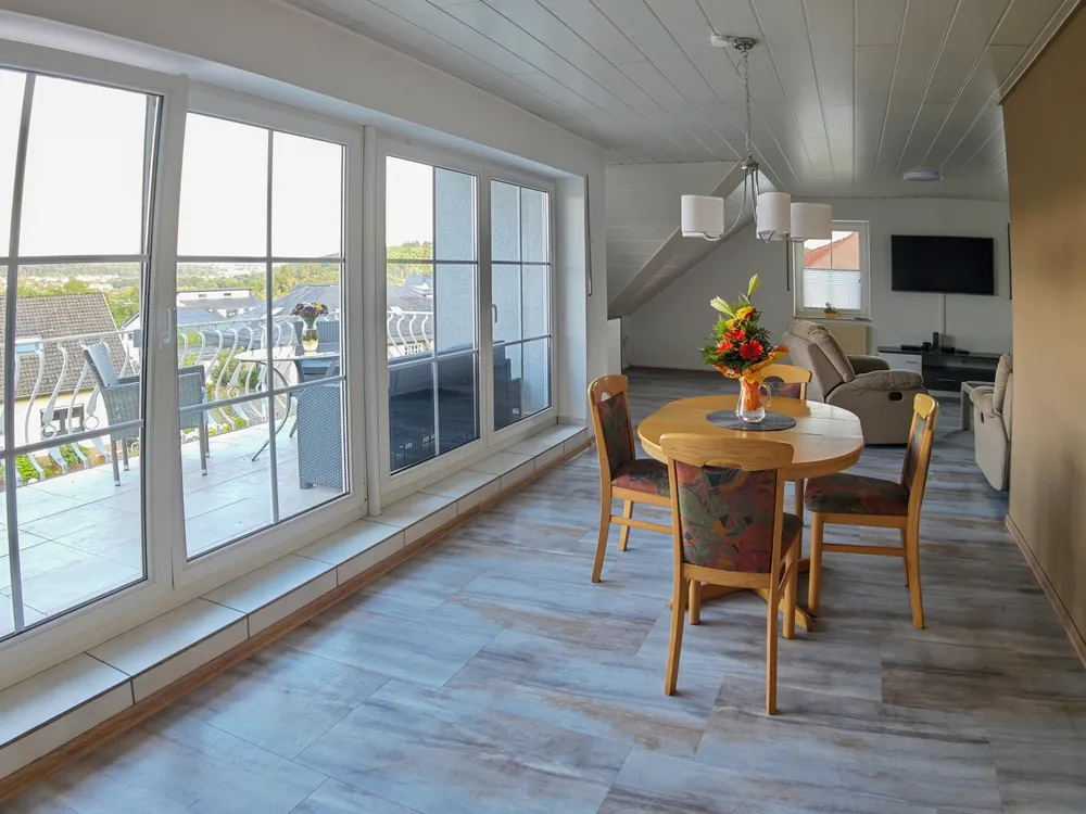 Heller Wohn- und Essbereich der Ferienwohnung in Sundern mit großer Fensterfront und Zugang zum Balkon