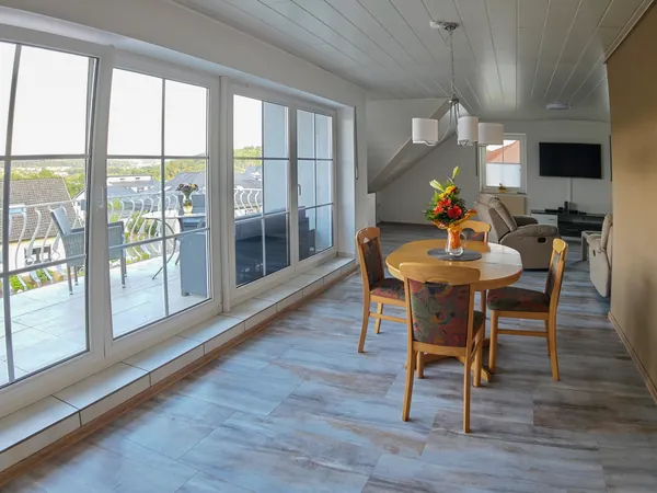 Heller Wohn- und Essbereich der Ferienwohnung in Sundern mit großer Fensterfront und Zugang zum Balkon