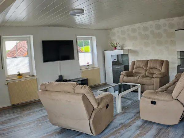 Wohnzimmer der Ferienwohnung am Sorpesee mit Sofa, bequemen Relaxsesseln und Smart-TV